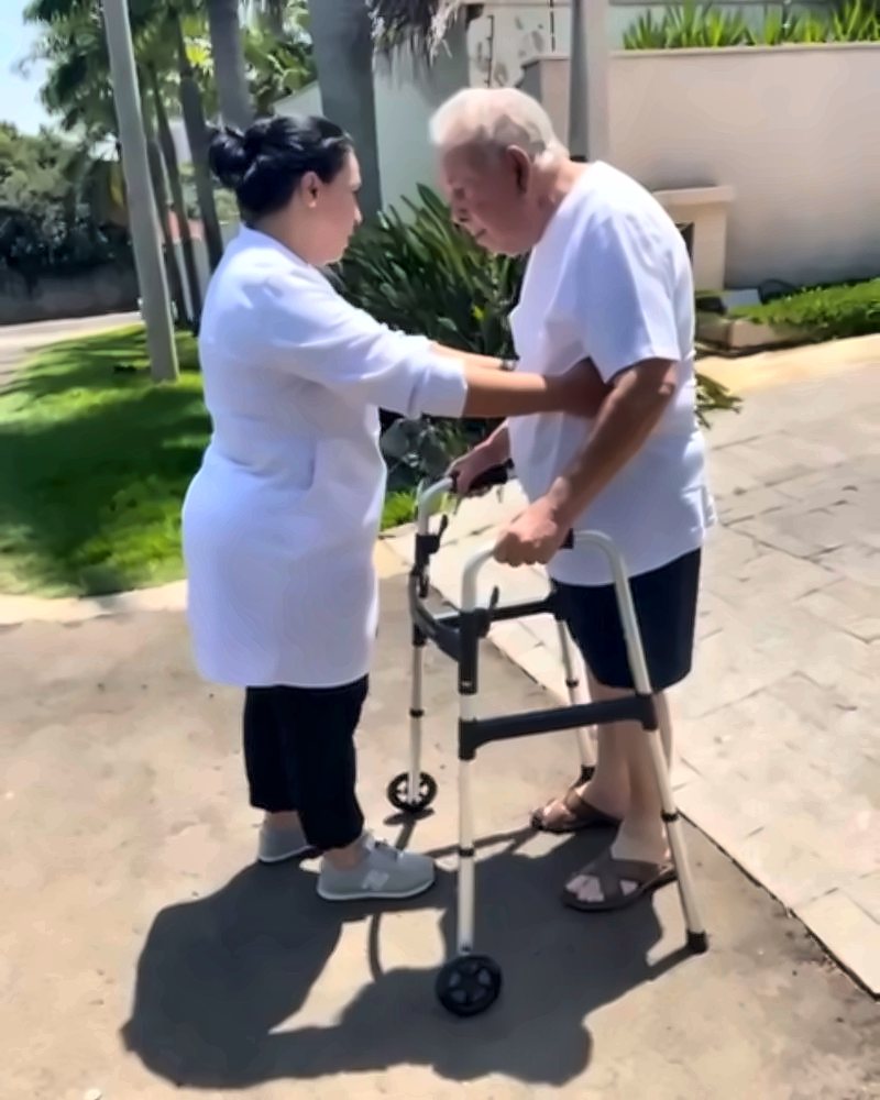 Dra. Talita acompanhando paciente idoso caminhando com andador