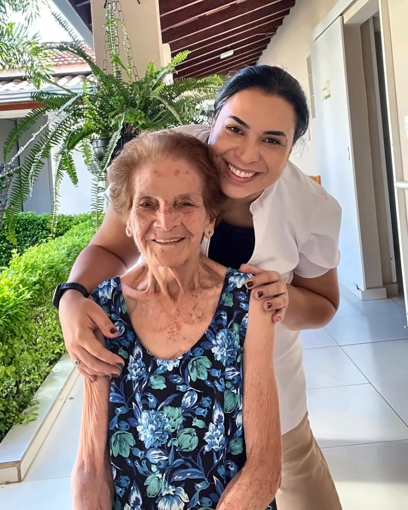 Dra. Talita abraçada a uma paciente idosa, as duas sorrindo
